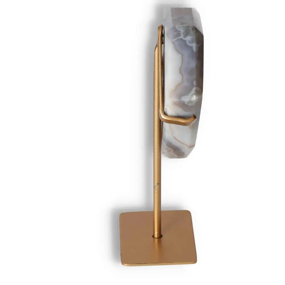 Side view of agate freeform decoration on a gold stand, highlighting natural patterns and polished surface.