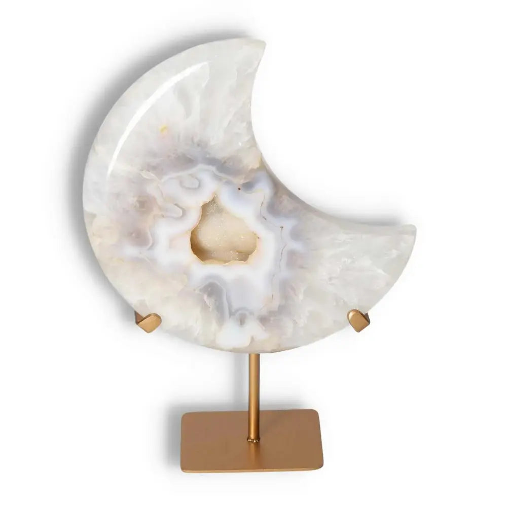Agate lunar crescent sculpture with geode center, displaying natural ivory swirls, mounted on a gold stand for home decor elegance.