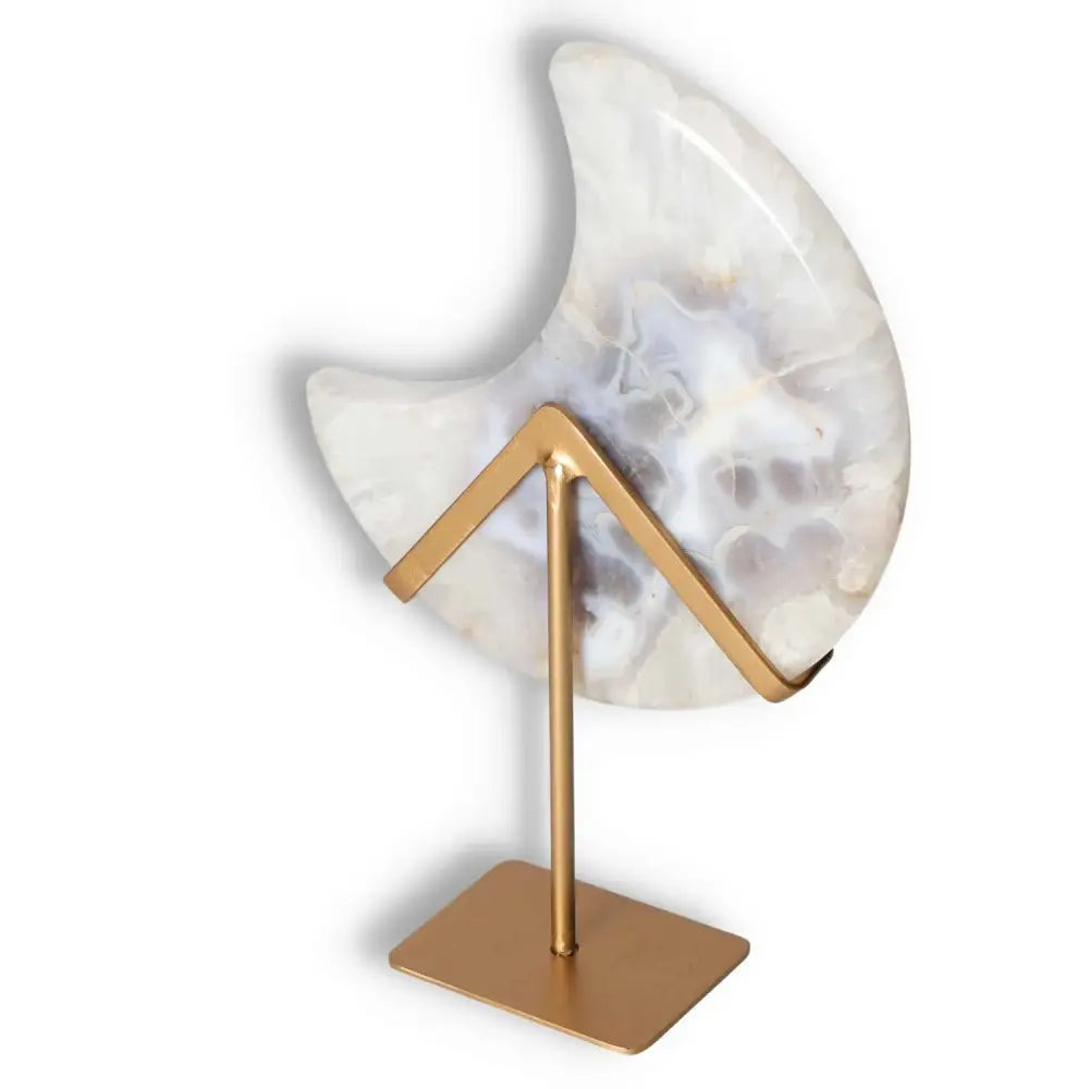 Agate lunar crescent on stand with translucent layers revealing soft, off-white swirls and a central geode formation, elegant and illuminating.