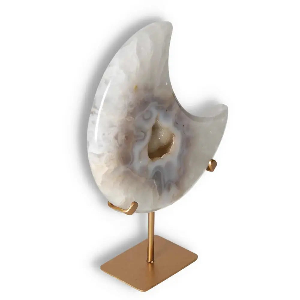 Agate lunar crescent with translucent layers and geode center, on a gold stand, illuminating with ethereal elegance.