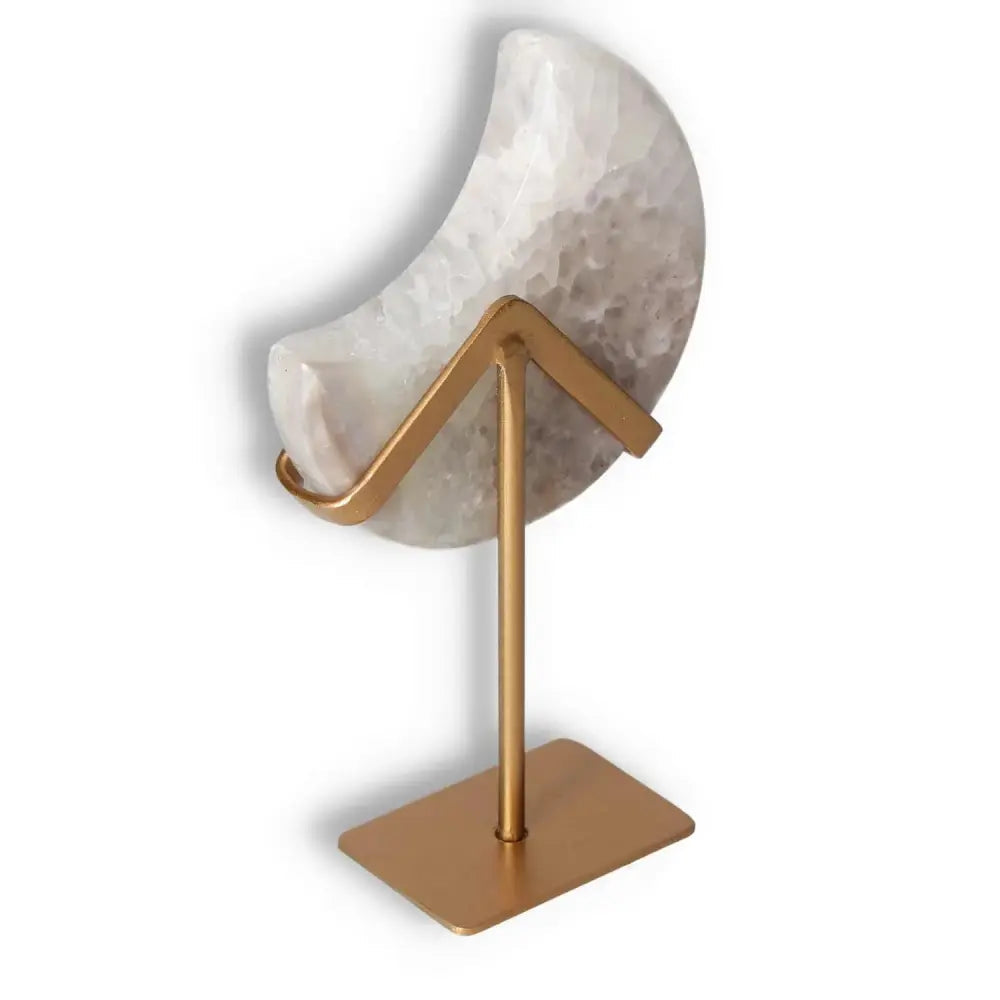 Agate lunar crescent ornament with natural geode, showcasing ethereal swirls in soft hues, placed on a sleek gold stand.