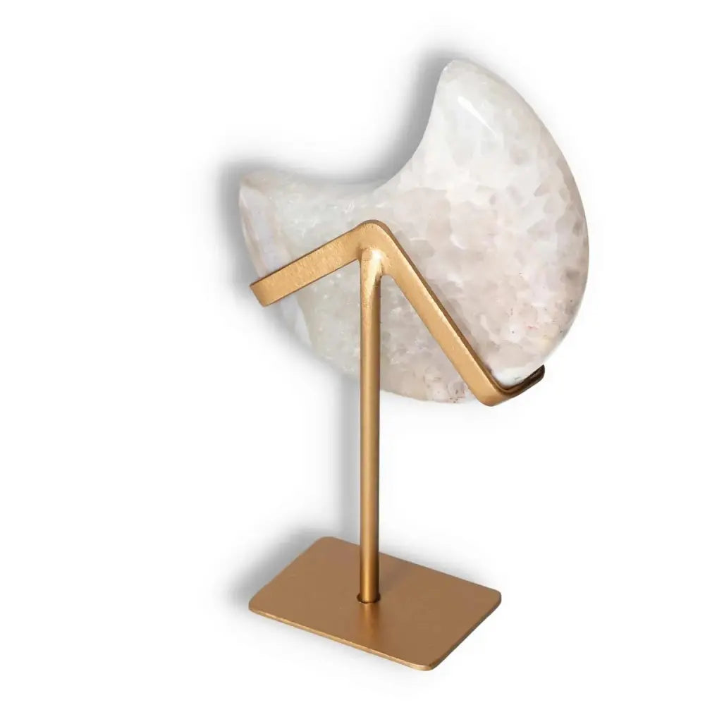 Agate lunar crescent sculpture with natural geode, displayed on a gold stand, showcasing translucent layers and delicate off-white hues.