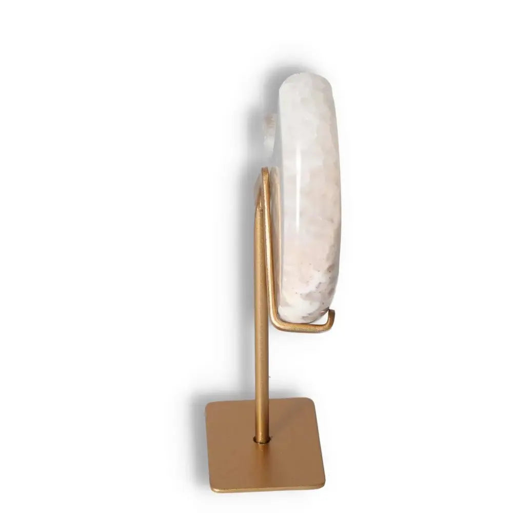 Side view of agate lunar crescent sculpture on a gold stand, showcasing its translucent layers and natural geode formation.