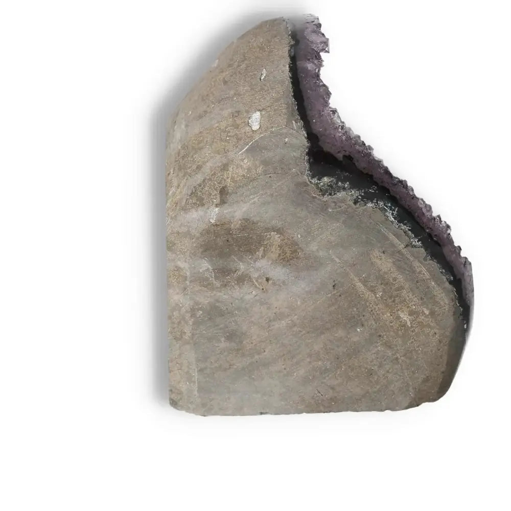 Side view of Amethyst Cut Base Geode by Sylvia Crystals, showcasing its raw exterior and stunning purple quartz interiors.