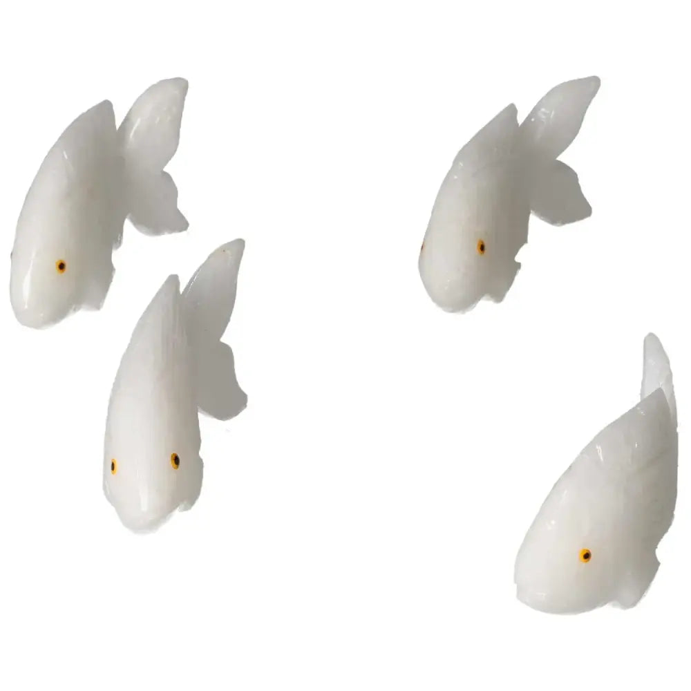 Four elegantly carved dolomite fish by Sylvia Crystals, showcasing white stonework and orange accents, symbolizing luxury and emotional balance.
