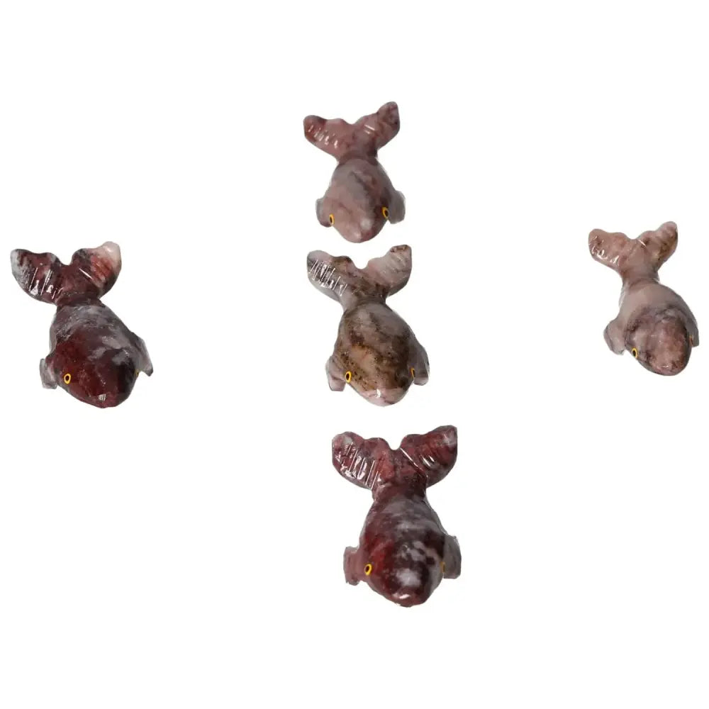 Group of five carved magnesite whale figurines on white background.
