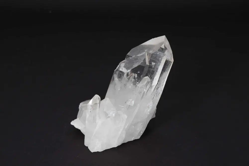 Clear Quartz Cluster on dark background, showcasing natural crystal points and high vibrational energy for purity and harmony.