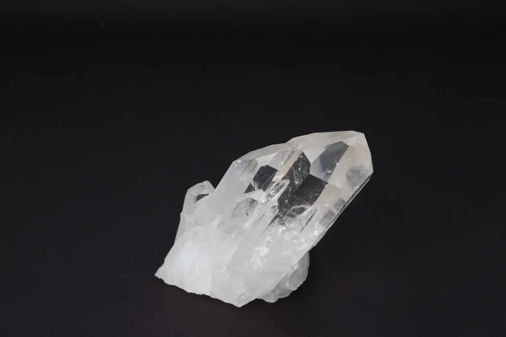 Clear Quartz Cluster on dark background, showcasing multiple crystal points and radiant clarity for amplifying energy and intention.