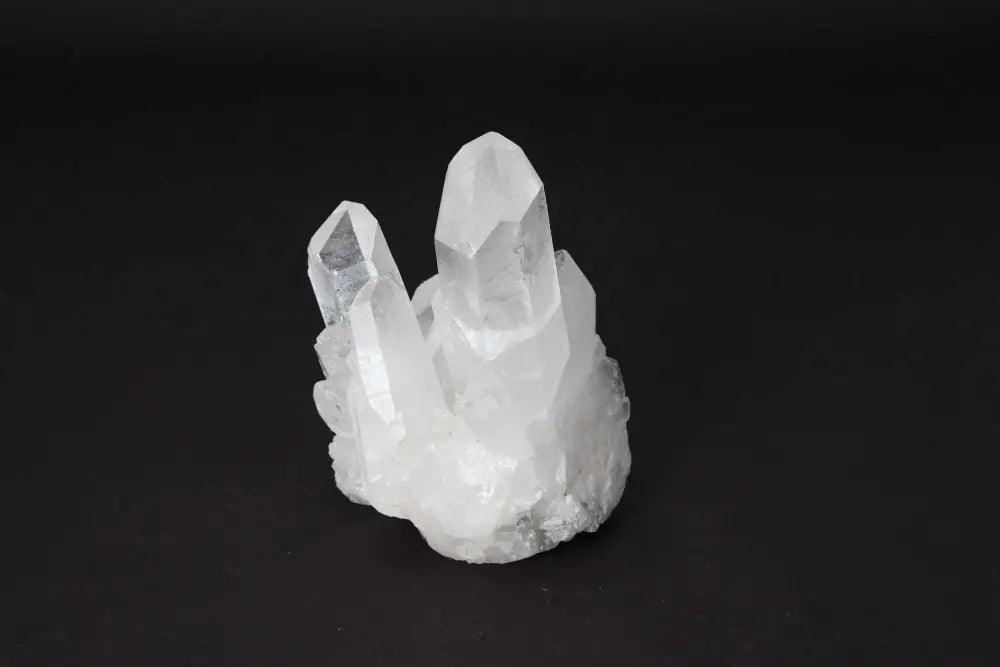 Clear Quartz Cluster on black background, showcasing multiple crystal points for energy amplification and purification.