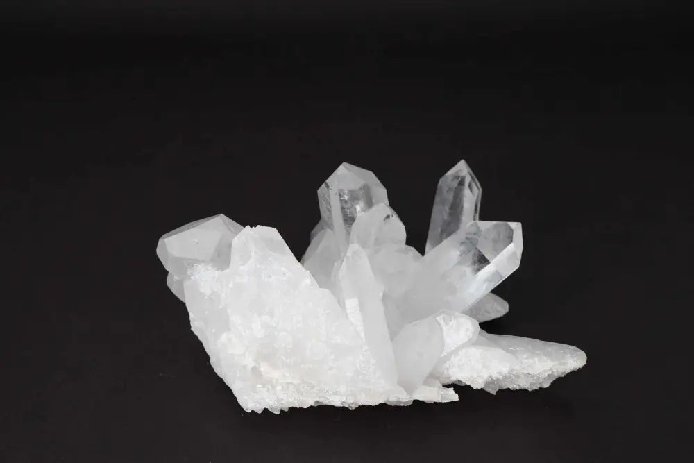 Clear Quartz Cluster with multiple crystal points on a dark background, radiating clarity and high vibrational energy.