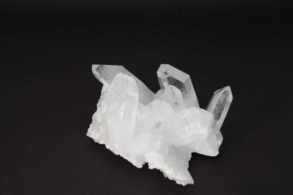 Clear Quartz Cluster on dark background showcasing its crystal points and energy amplifying properties.