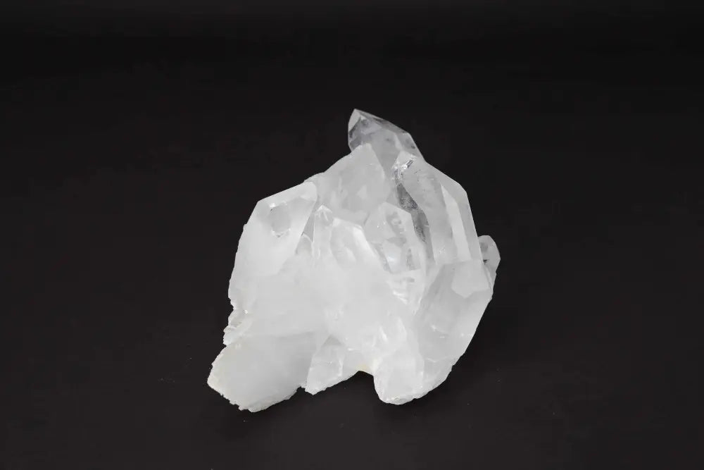 Clear Quartz Cluster on dark background, showcasing natural crystal formations and points radiating energy and light.