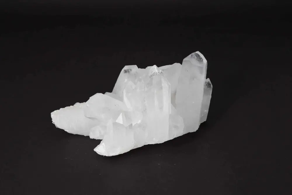 Clear Quartz Cluster radiating clarity and energy, featuring multiple crystal points on a dark background.