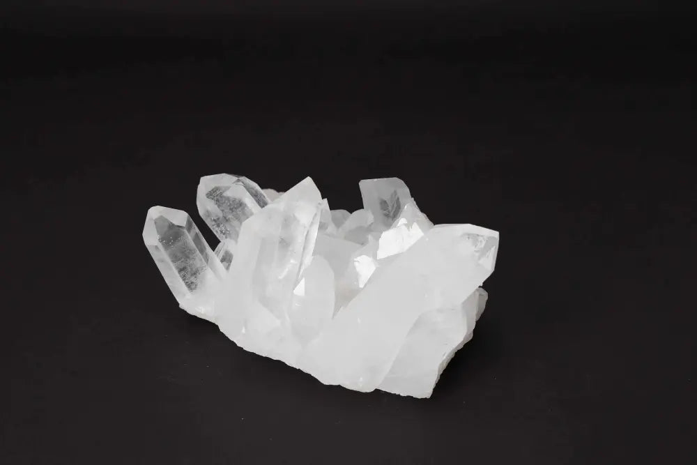 Clear Quartz Cluster on black background radiating clarity and high vibrational energy, featuring multiple crystal points on a shared matrix.