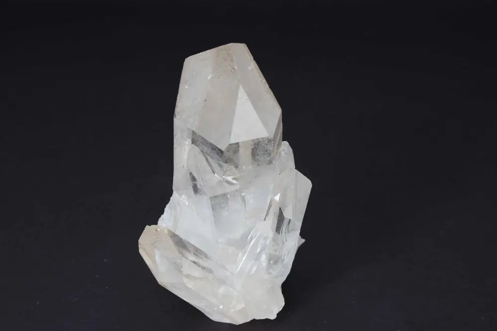 Clear Quartz Cluster on dark background, showcasing crystal points for energy amplification and purification.
