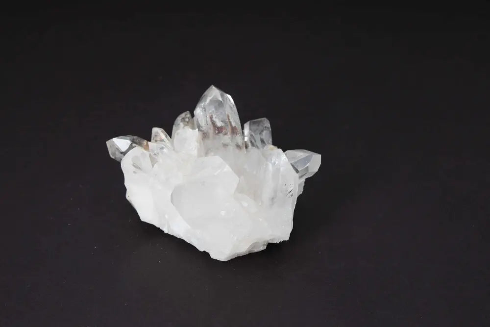 Clear Quartz Cluster on black background, showcasing multiple crystal points for energy amplification and space harmonization.