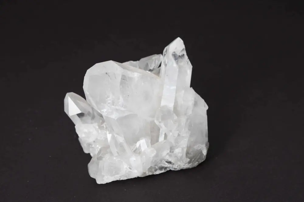 Clear Quartz Cluster on dark background, showcasing natural crystal formations and high vibrational energy for space harmony.