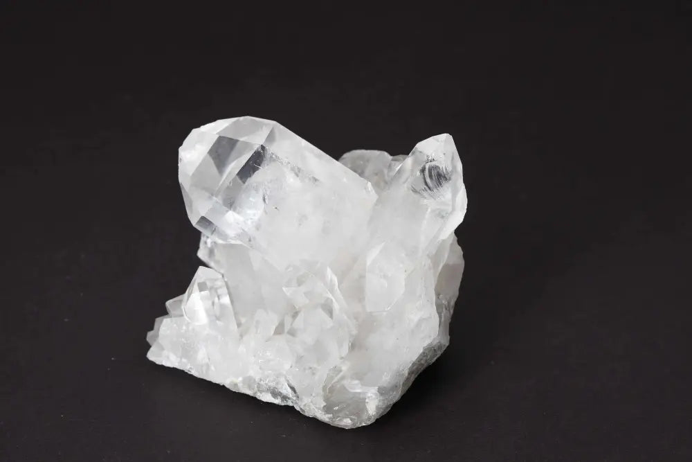 Clear Quartz Cluster crystal on dark background, showcasing natural formations with multiple points and high vibrational energy.
