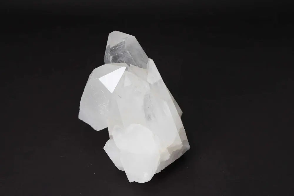 Clear Quartz Cluster radiating energy and clarity, featuring multiple crystal points on a dark background, ideal for energy cleansing.