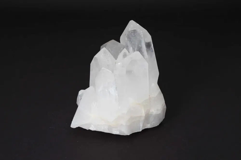 Clear quartz cluster on black background, featuring multiple crystal points for energy amplification and purification.