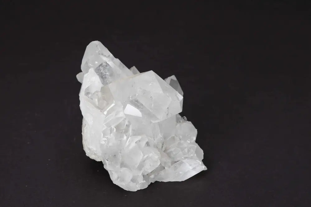 Clear Quartz Cluster on dark background showcasing multiple crystal points for amplifying energy and purifying spaces.