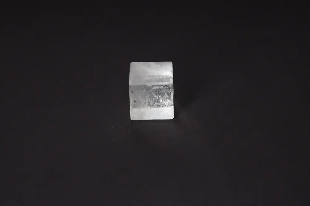 Clear Quartz Cube 4cm on dark background, known for purification and neutralizing negative vibrations. Ideal for harmonizing body, mind, energy.
