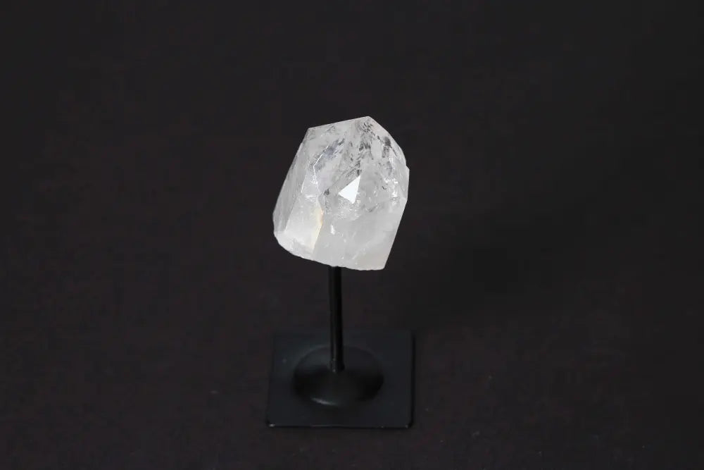 Clear Quartz crystal on a sleek metal stand against a dark background, showcasing its luxurious and spiritual essence.