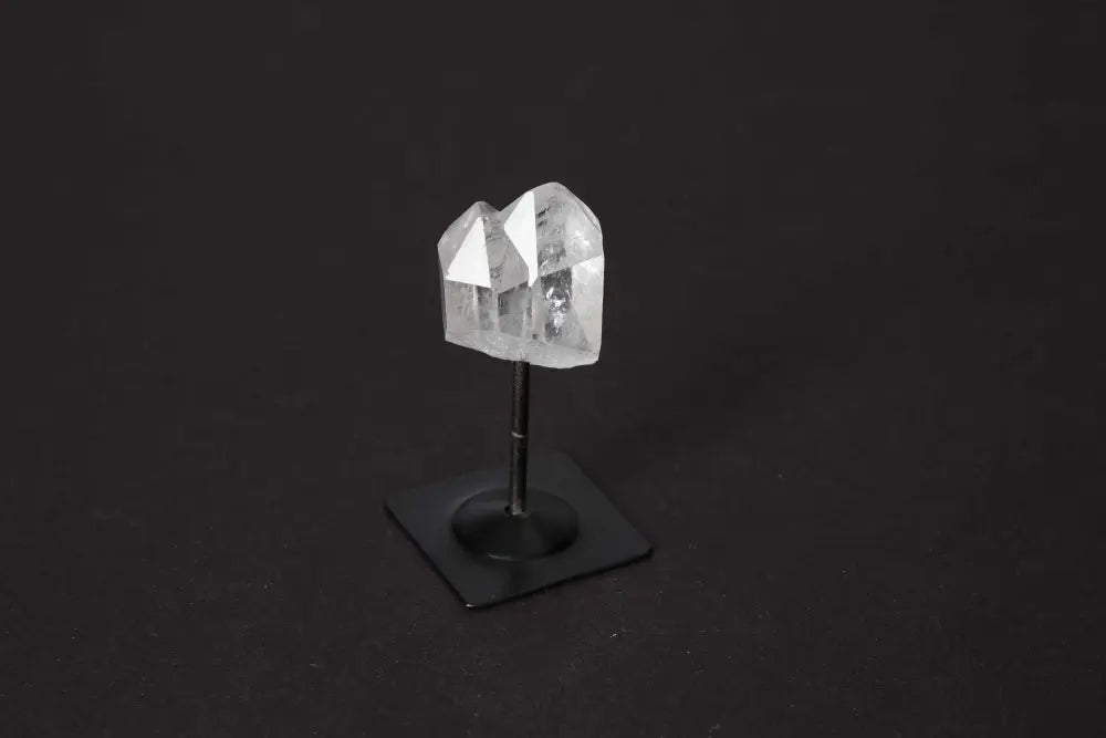Clear quartz crystal on metal stand for chakra balancing and spiritual support, highlighting energetic properties and zodiac alignment.
