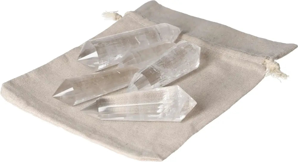Five Clear Quartz points on a beige fabric pouch, known for purification and harmonizing body, mind, and energy.