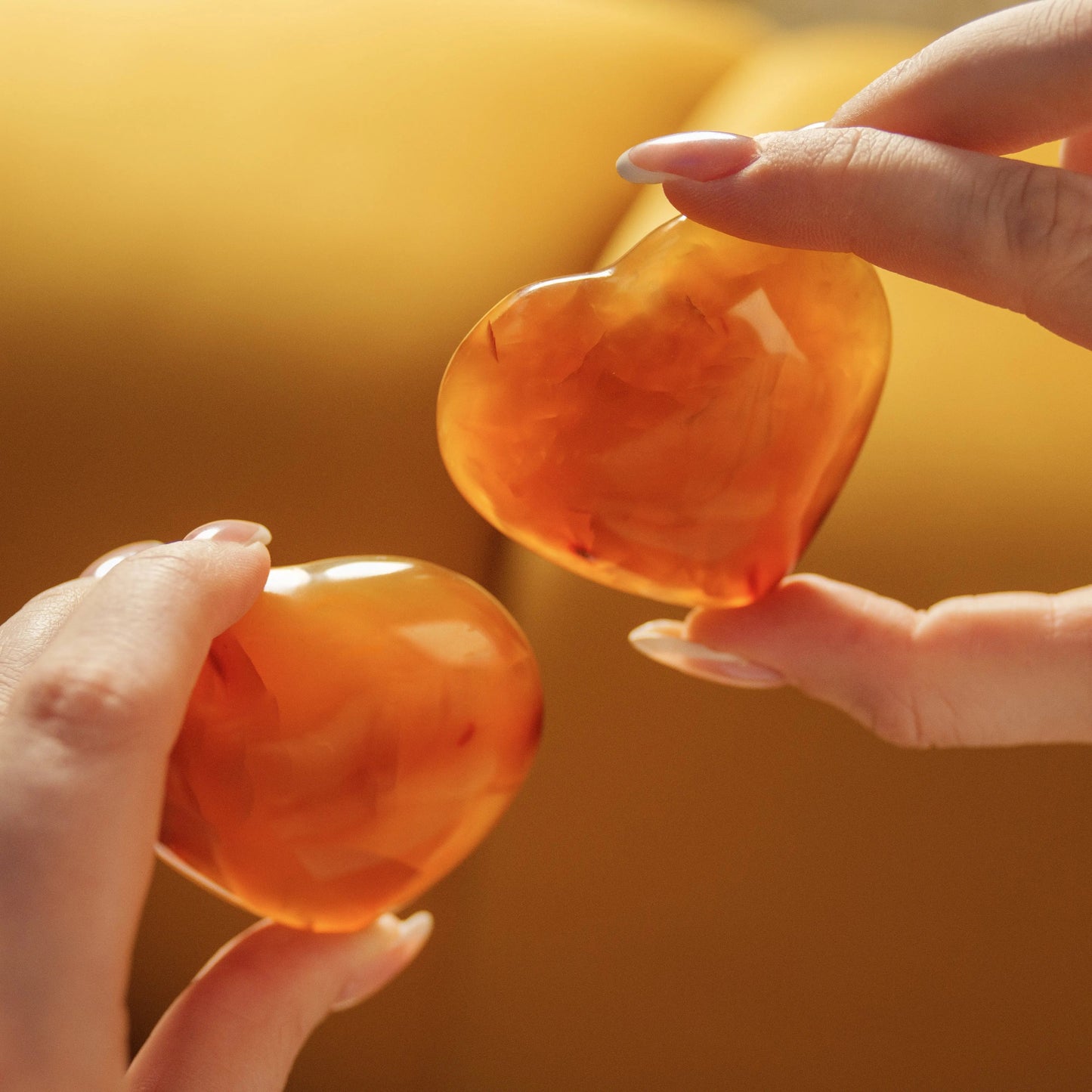 Hands holding two polished Carnelian Hearts from the Eternal Love Gift Box, symbolizing passion and love for Valentine's Day.