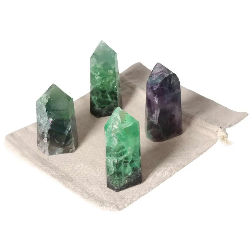 Four fluorite crystal points on a beige pouch, totaling 1 KG, enhancing creativity and learning with green and purple hues.