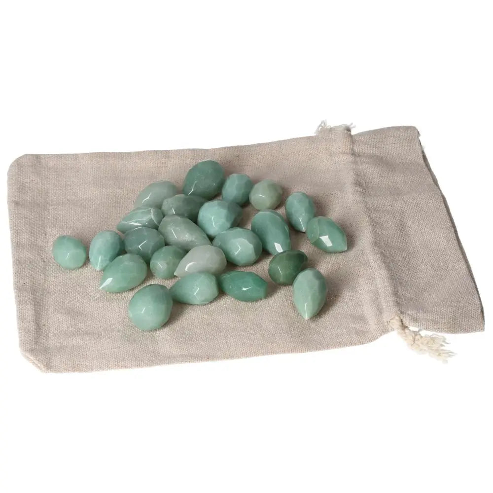 A collection of small green aventurine stones on a beige cloth, symbolizing luck, prosperity, and inner peace.