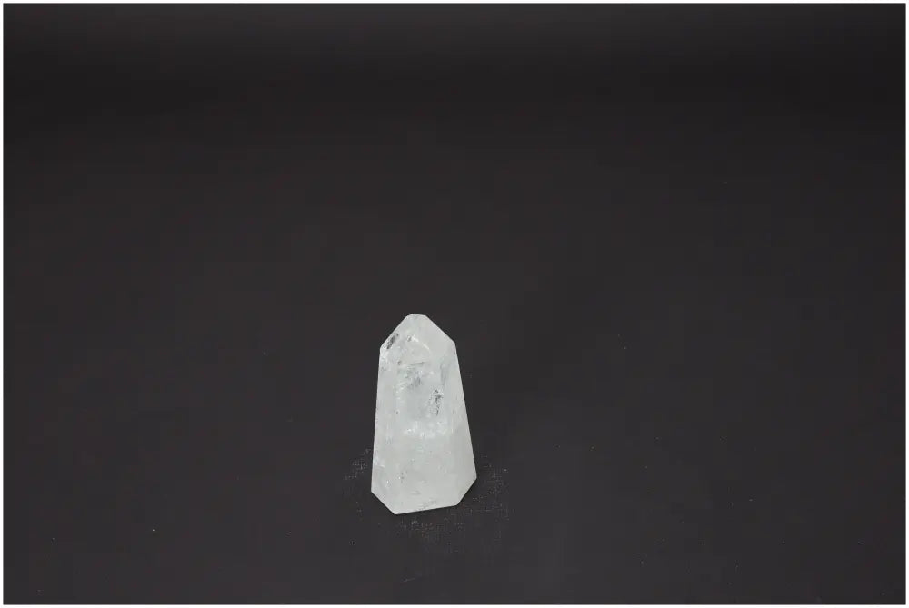 Clear Lemurian Quartz obelisk with unique properties for chakra and zodiac energy alignment against a dark background.