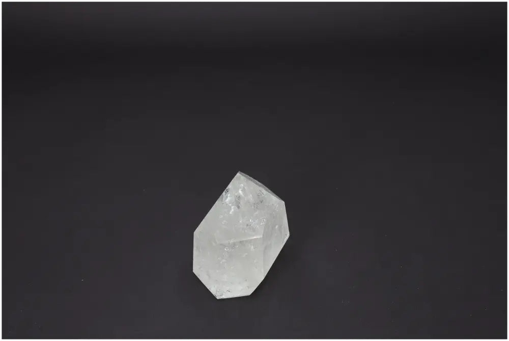 Clear Lemurian Quartz Obelisk on dark background, enhances energy and aligns chakras, spiritually supporting with unique quartz properties.