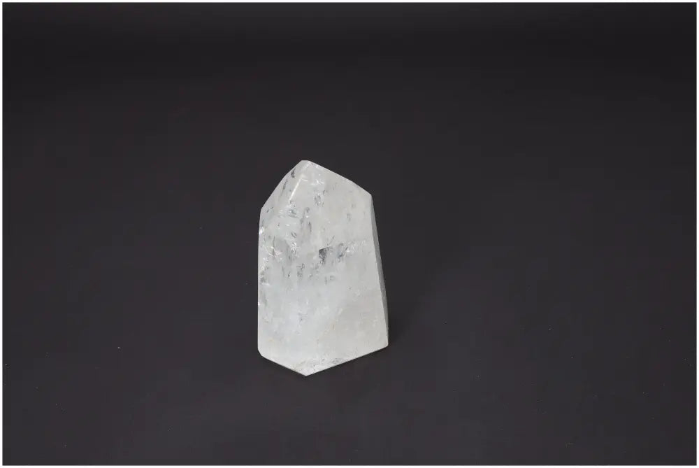 Lemurian Quartz Obelisk with spiritual energy properties, supports chakras and zodiac signs, clear crystal against black background.