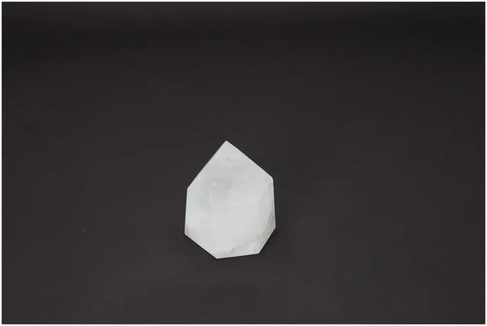 Clear Lemurian Quartz obelisk against a black background, showcasing its unique spiritual properties and chakra energies.