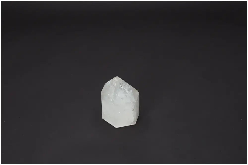 Clear Lemurian Quartz Obelisk on black background, believed to support chakras and enhance spiritual energy through unique mineral properties.