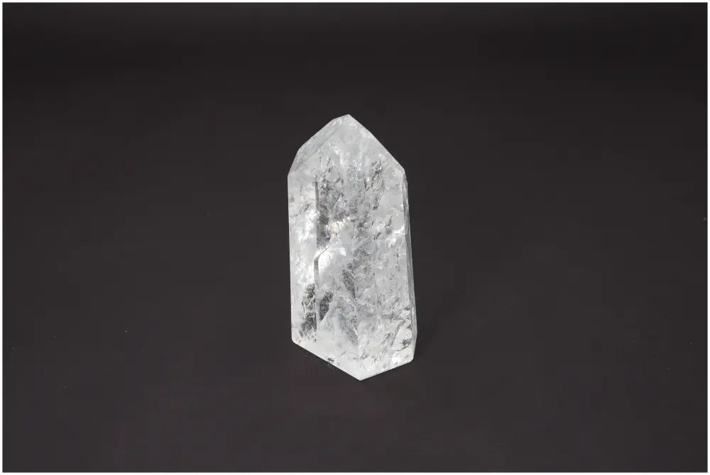 Lemurian Quartz Obelisk on a dark background, showcasing clear crystal structure with spiritual and energetic chakra properties.
