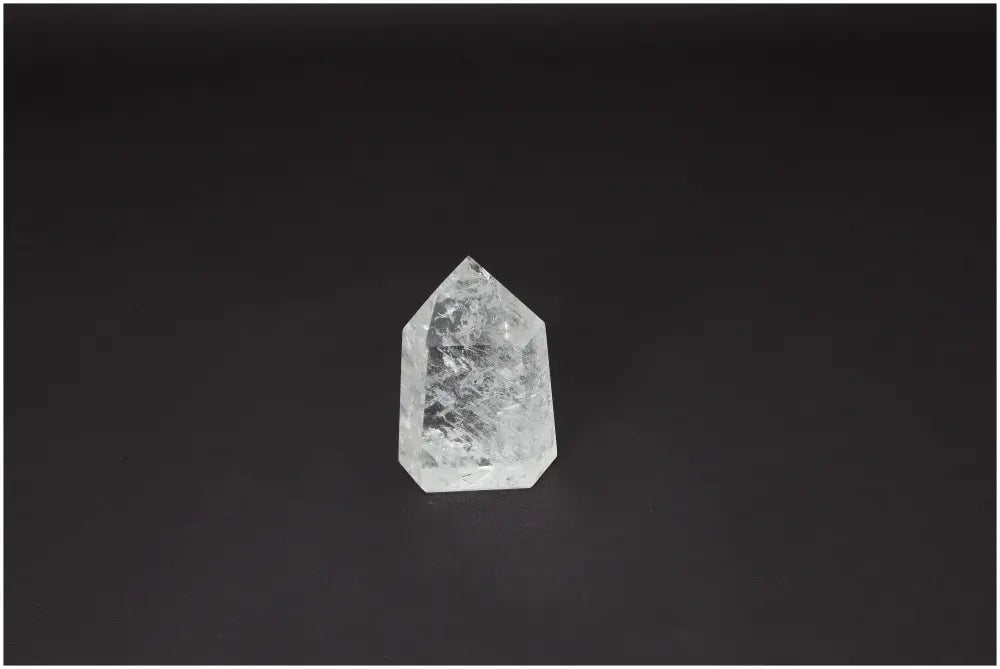 Lemurian Quartz Obelisk on a dark background, exhibiting clear crystal properties, associated with chakras and energetic healing.