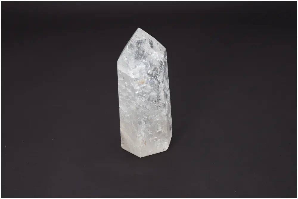 Clear Lemurian quartz obelisk for chakra alignment and spiritual enhancement on a dark background.