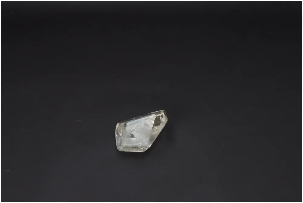 Clear quartz crystal on a dark background, showcasing natural clarity and facets, known for energetic and spiritual properties.