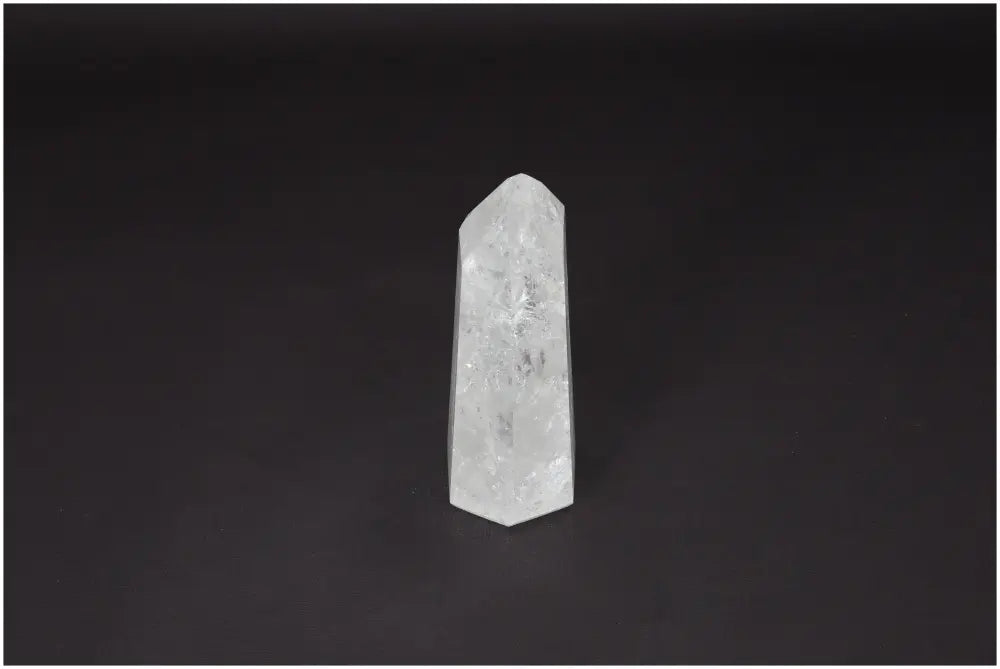 Lemurian Quartz Obelisk on dark background, embodies clarity and balance, ethically sourced clear quartz for personal growth.