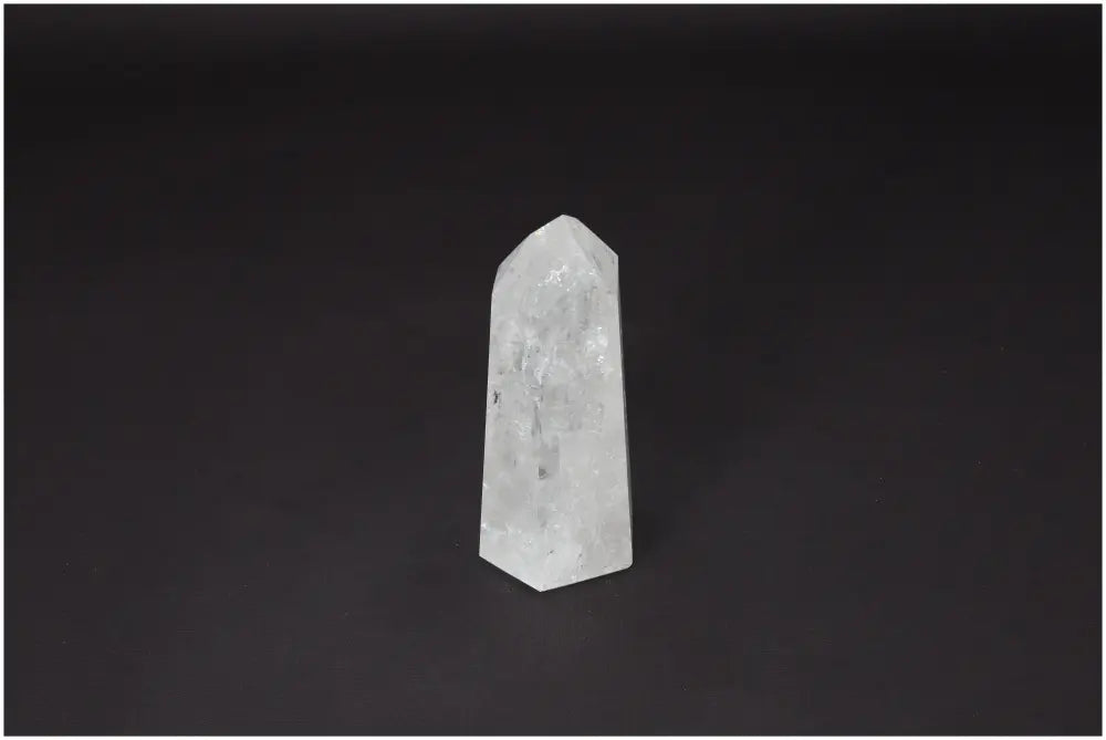 Lemurian Quartz Obelisk for clarity and balance, ethically sourced clear quartz crystal against a dark background.