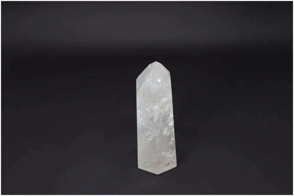 Lemurian Quartz Obelisk, a clear crystal known for clarity and healing, stands on a dark background, enhancing energy and balance.
