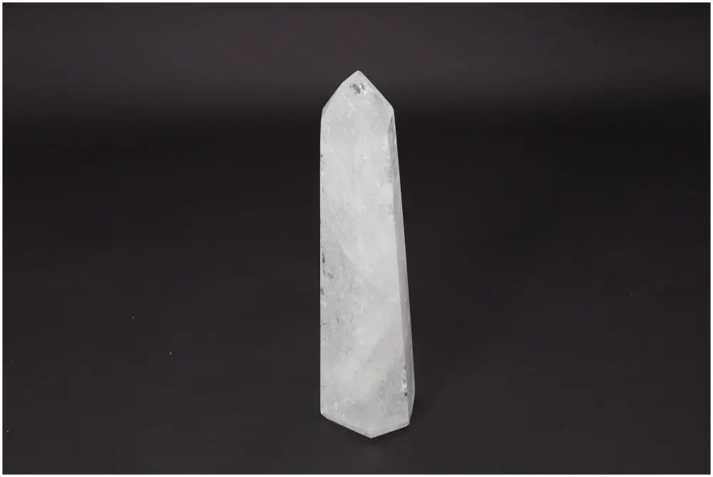 Lemurian Quartz Obelisk on black background, clear crystal known for enhancing clarity and personal growth, ethically sourced and natural.