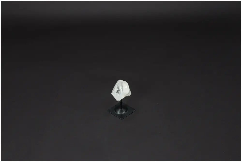 Lemurian Clear Quartz crystal on metal stand against dark background, symbolizing energy amplification and personal growth.