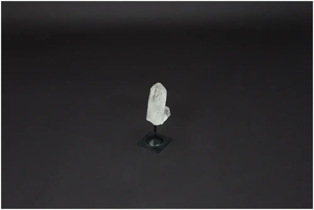 Lemurian Quartz on metal stand, powerful clear quartz for purification, harmonizing energy, and neutralizing radiation, against dark background.