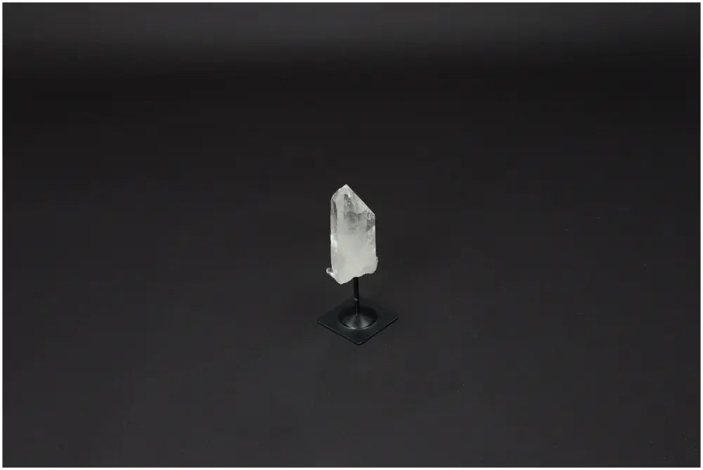 Lemurian Quartz crystal on a sleek metal stand, known for purification and harmonizing mind, body, and energy, against black background.