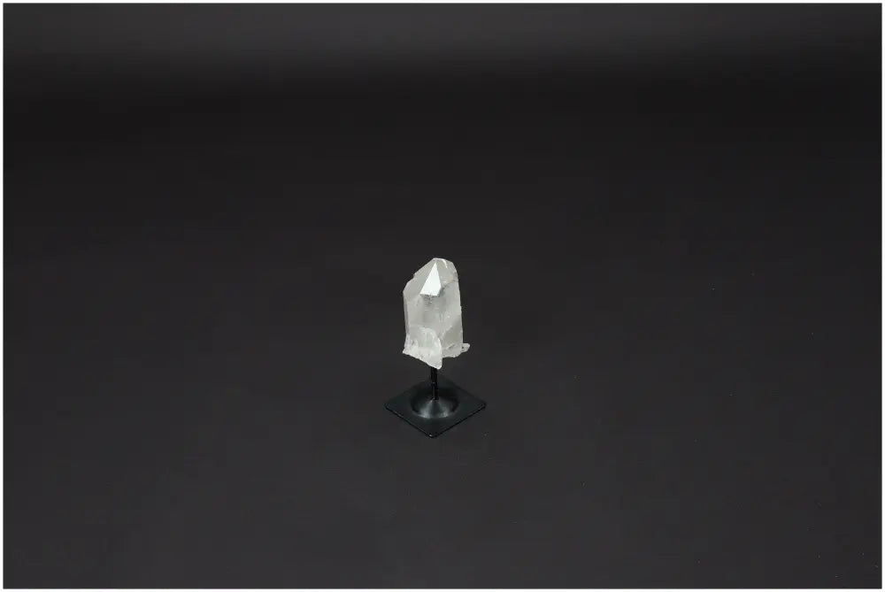Lemurian Quartz on metal stand against dark background, showcasing its clarity and purifying properties.
