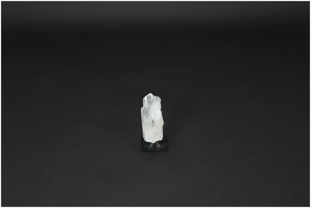 Lemurian Quartz on metal stand, a powerful Clear Quartz crystal for purification and harmonizing energy, against a dark background.